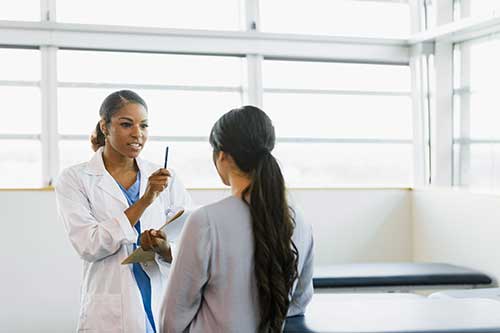 woman doctor giving female patient eye exam